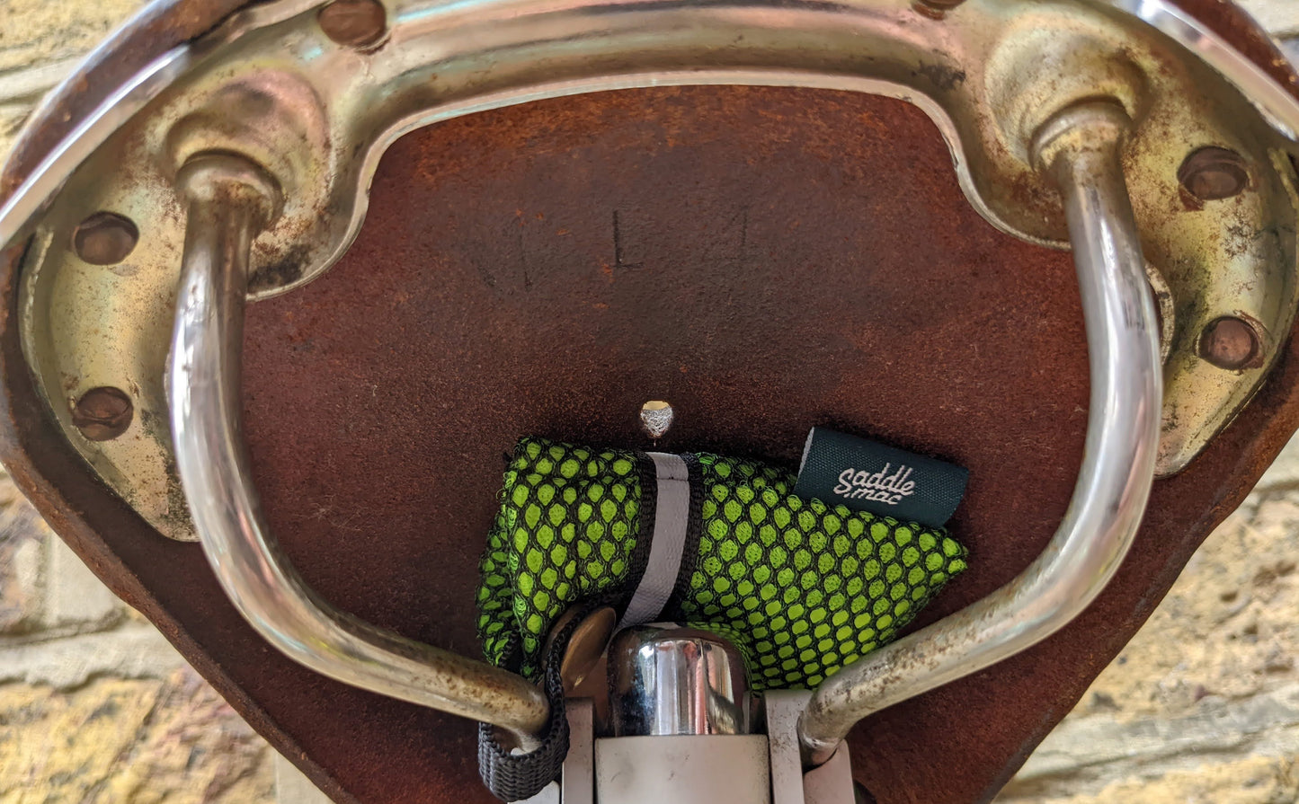 Saddlemac storage pouch ticked neatly underneath a leather bicycle saddle.