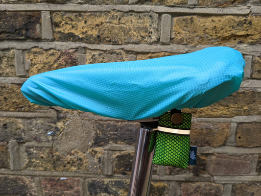 Saddlemac turquoise saddle rain cover against a brick wall